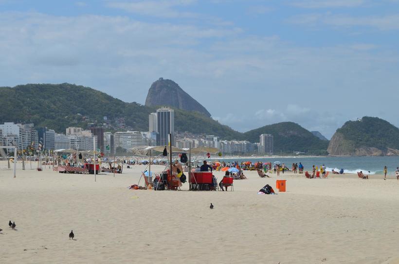 Отдыхающие на пляже Копакабана. Большинство присутствующих притащило зонтики и пляжные кресла с собой